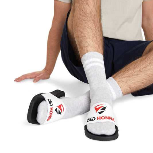 Model standing in white Zed Honra sandals with red logo, paired with socks.
